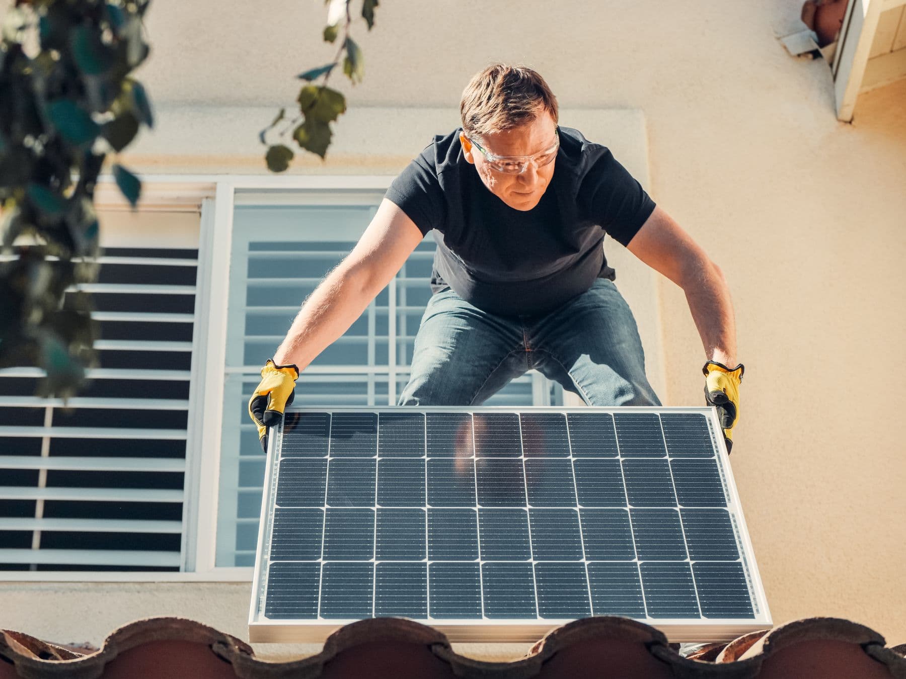 Instalador posicionando um módulo fotovoltaico em telhado de cerâmica